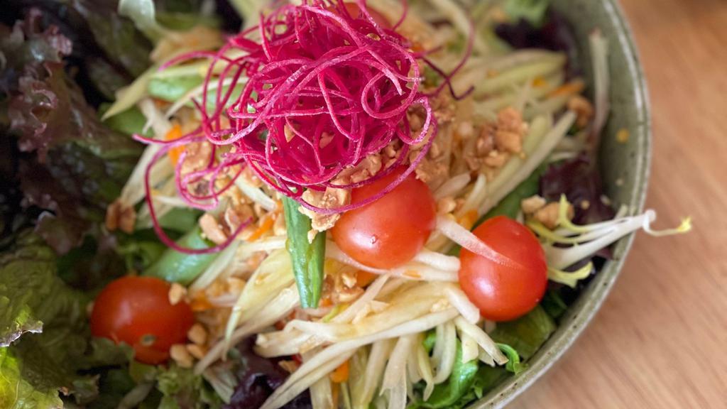 Papaya Salad · Shredded green papaya, carrots, green beans, tomatoes, chili, ground peanuts, and garlic tossed with a chili-lime dressing