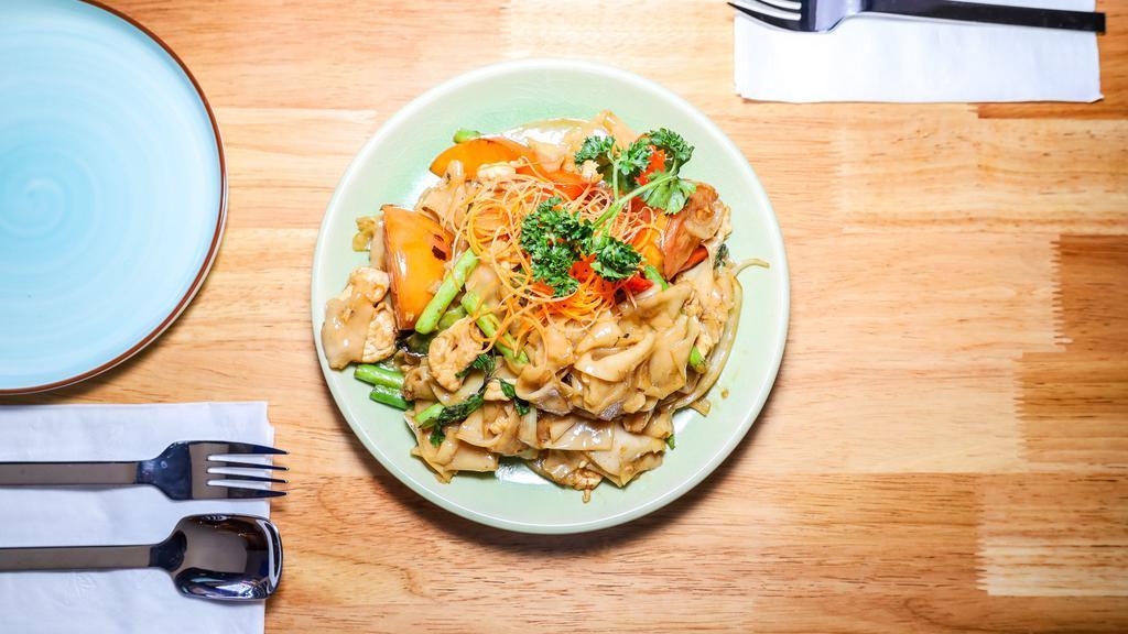 Pad Kee Mao · Flat rice noodles stir-fried with a homemade spicy sauce, choice of protein, bell peppers, white onions, green beans, tomatoes, and basil.