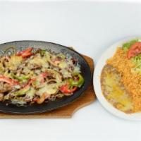 Alambres · Chunks of beef steak, onions, bell pepper, bacon, rice, beans, sour cream, guacamole, salad ...