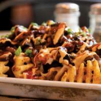 Swamp Fries · waffle fries tossed in house rub with . poblano queso, smokey baked beans, . chopped brisket...
