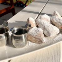 Warm Beignets · rustic donuts, smothered in powdered sugar and served with warm caramel and chocolate sauces