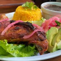POLLO ASADO · Baked chicken rubbed in anatto seasoning, served with rice, black beans, side salad and hand...