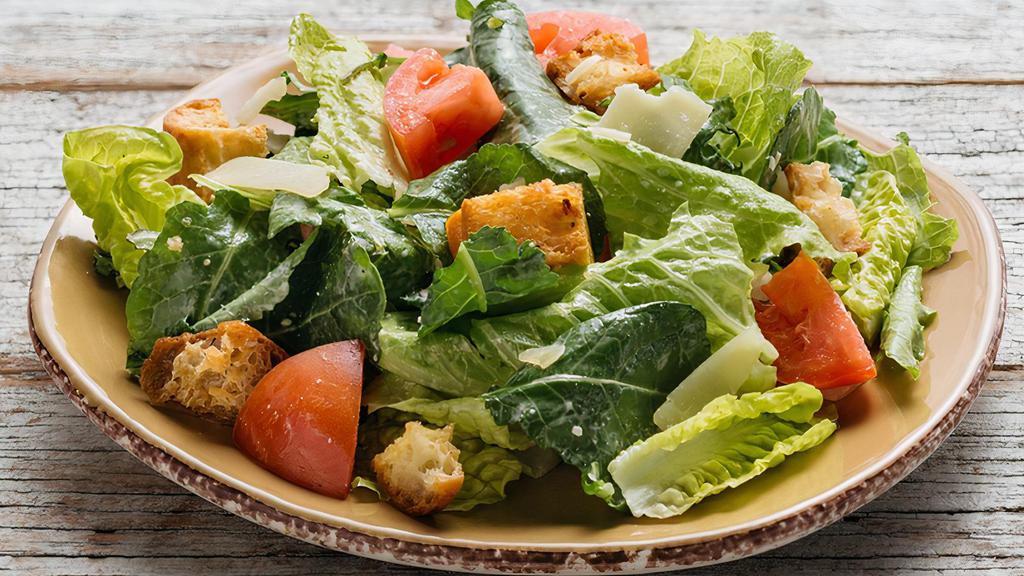 Side Caesar Salad · hand cut organic romaine and organic whole baby kale leaves tossed with diced organic tomatoes, crunchy roasted garlic croutons, shaved asiago cheese, creamy house made Caesar dressing