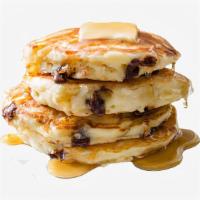 Chocolate Chip Pancakes · Three rich chocolate chip pancakes with syrup and butter on the side.