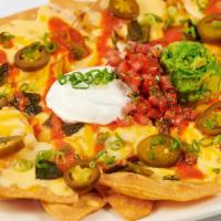 Factory Nachos · Crisp Tortilla Chips Covered with Melted Cheeses, Guacamole, Red Chile Sauce, Sour Cream, Ja...