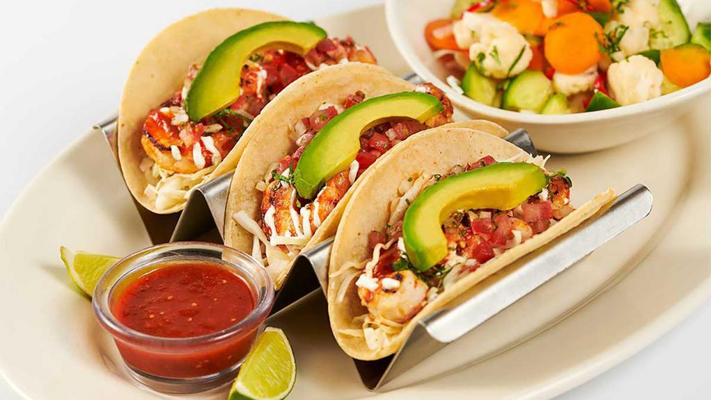 Skinnylicious® Shrimp Soft Tacos · Three Soft Corn Tortillas Filled with Shrimp, Avocado, Tomato, Onions, Cilantro and Crema. Served with Escabeche Vegetable Salad