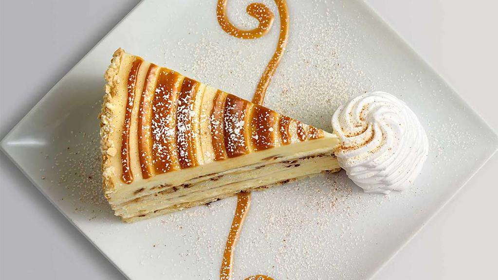 Cinnabon® Cinnamon Swirl Cheesecake · Layers of Cinnabon® Cinnamon Cheesecake and Vanilla Crunch Cake Topped with Cream Cheese Frosting and Caramel