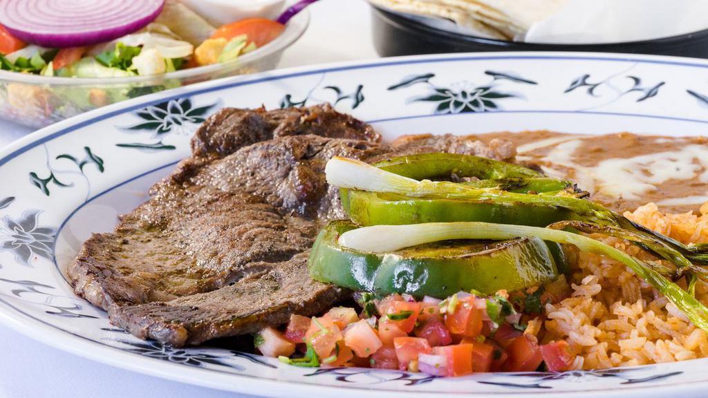 Carne Asada Plate · Grilled steak garnished with green onions and bell peppers, served with rice, refried beans, pico de gallo, tortillas and a side salad.