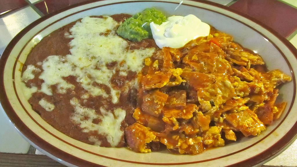 Chilaquiles · Lightly Fried Corn Tortilla Chips, Scrambled Eggs, Simmered in our Mild Red Sauce, Topped with Sour Cream and Guacamole