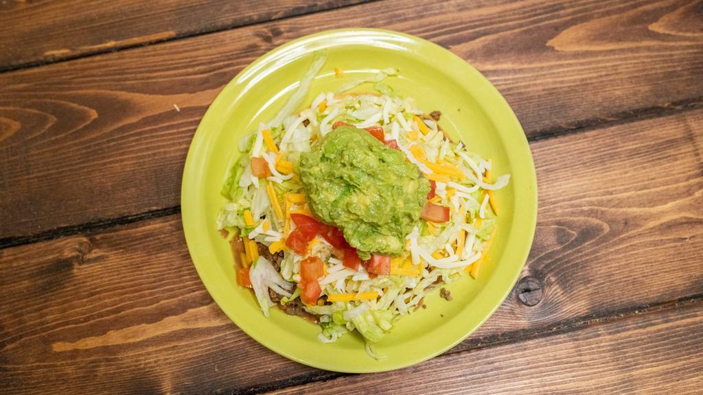 Tostada · Fried corn tortilla topped with beans, your choice of meat, cheese, lettuce, tomato and avocado.