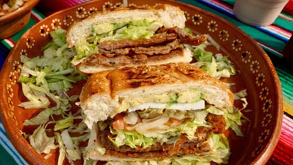 Torta de Milanesa · Toasted bread with a breaded slice of beef, beans, lettuce, onions, tomatoes, jalapeños, sliced avocado and queso fresco.