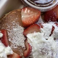 Pancakes with Fruit · Large pancakes topped with fresh strawberries, bananas, pecans, whipped cream, and warm mapl...
