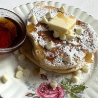 White Chip Buttermilk Pancakes · 2 large buttermilk white chocolate chip pancakes with syrup and butter.