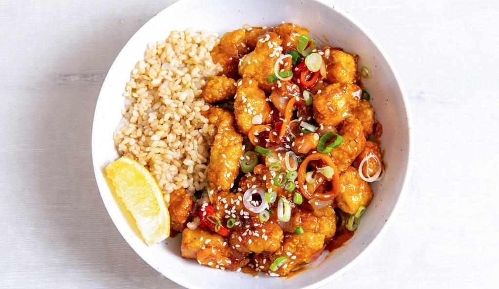 Thrive Orange Chicken Bowl · Antibiotic-free, oven-fried chicken with charred peppers, caramelized onions, green onions, sesame seeds, and our house-made orange sesame sauce. Served with a lemon wedge, and a base of your choice. Gluten-free.