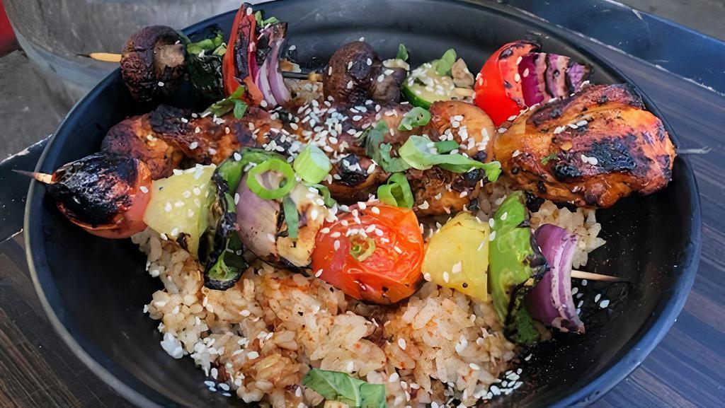 Grilled Skewer Rice Bowl · A rosemary rice bowl with grilled chicken and choice of vegetable skewer, topped with choice of sauce, green onions, sesame seeds, and dash of togarashi spice.