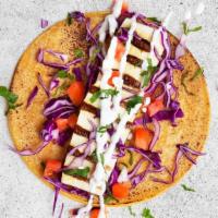 Grilled Halloumi Taco · Grilled halloumi with shredded cabbage, tomatoes, tzatziki, and cilantro in a flour tortilla.