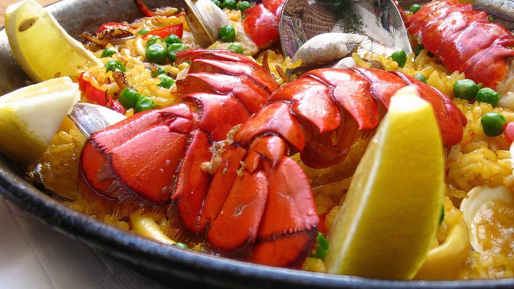 Paella de Langosta · Lobster tail paella with calamari and clams.