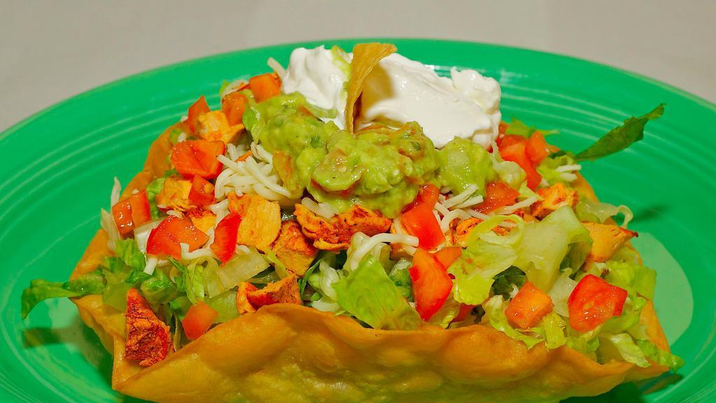 Taco Salad · Crispy flour tortilla shell filled with meat, rice, beans, sour cream, lettuce, guacamole, tomatoes, cheese.