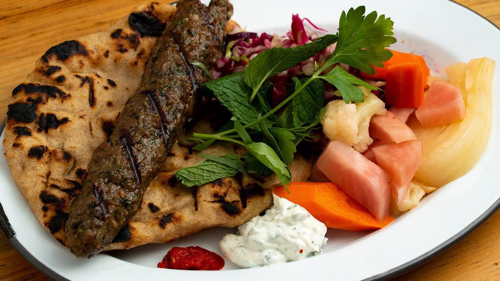 Lamb Plate · One grilled lamb kebab (ground organic lamb with lovage, mint, parsley, cardamom, and cumin), choice of grilled homemade flatbread, or mashed red lentils, choice of two salads, herby yogurt, and spicy pickled chiles. (red lentils are gluten-free).