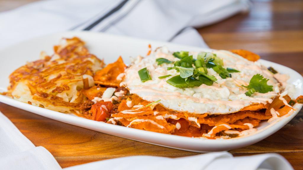 Chilaquiles · Corn tortilla chips tossed in salsa roja, tomatoes, onion, jalapeños. chorizo, topped with two eggs any style