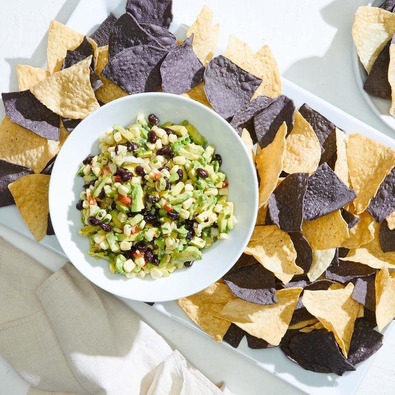 Catering White Corn Guacamole + Chips · Diced avocado, sweet corn, black beans, jicama, bell peppers, fresh cilantro and serrano peppers. Served with housemade blue & white corn tortilla chips.  .