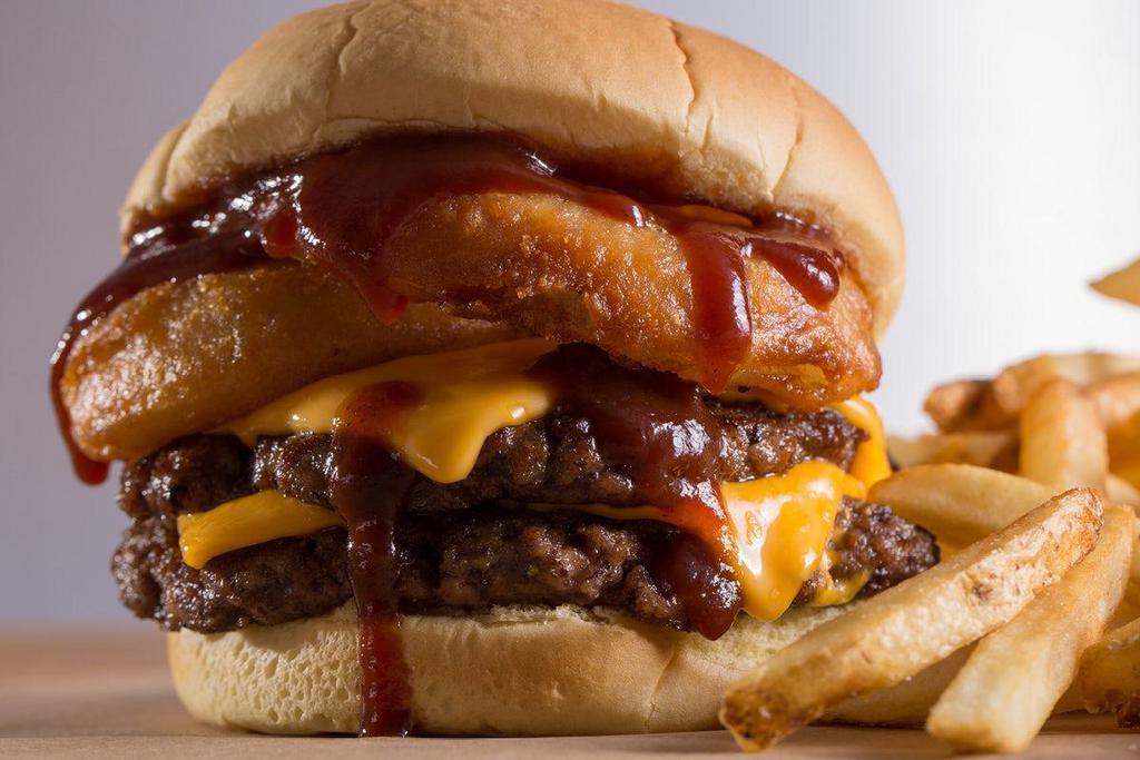 Rodeo Burger · A two-patty Texan delight. Topped with cheddar cheese, our signature crispy onion rings, and a BBQ sauce tangy enough to kick anyone off their mechanical bull.