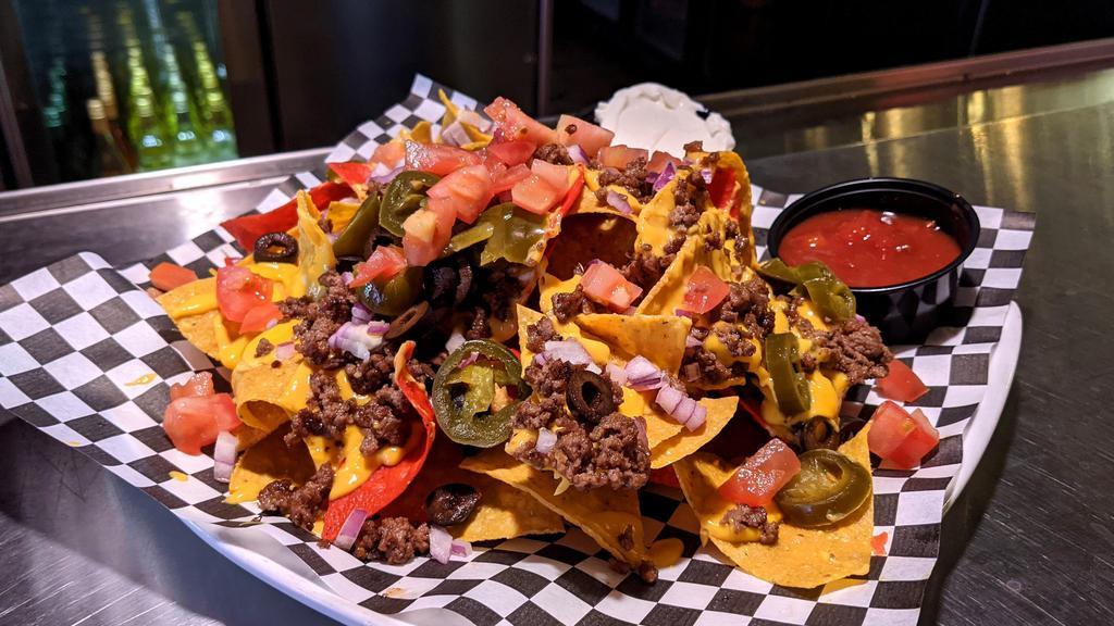 Nachos · layered with cheese, tomatoes, onions, olives & jalapenos. w/ ground beef or chicken +5.00