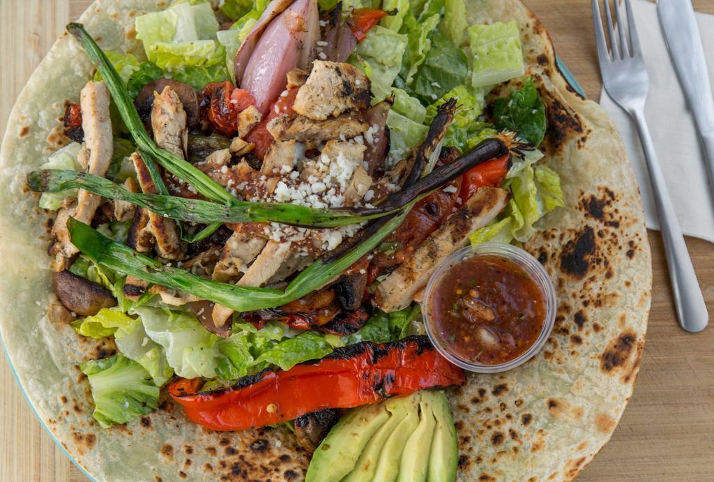 Fajita Salad · Flame grilled meats and vegetables (red bell and jalapeno pepers, red and green onions, tomato & mushrooms) on a bed of romaine in a creamy cilantro dressing atop a charred tortilla with re-fried beans, avocado, roasted tomato and cotija cheese.
