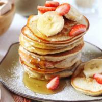 Strawberry & Banana Pancakes · Perfectly fluffy pancakes topped with bananas and strawberry served with a side of butter an...