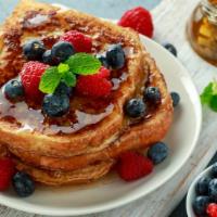Blueberry French Toast · Fresh baked bread dipped in a rich egg batter topped with blueberries with a side of butter ...