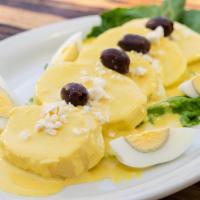 Papita a la Huancaina · Slices of boiled potatoes topped with Aji Amarillo chili and cheese sauce, garnished with Qu...