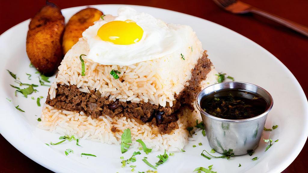 Tapado a lo Pobre · A traditional Peruvian comfort food, ground Certified Angus Beef stew made with raisins, olives, onions, tomatoes and soy sauce, served with garlic jasmine rice, topped with a fried egg and fried sweet plantains.