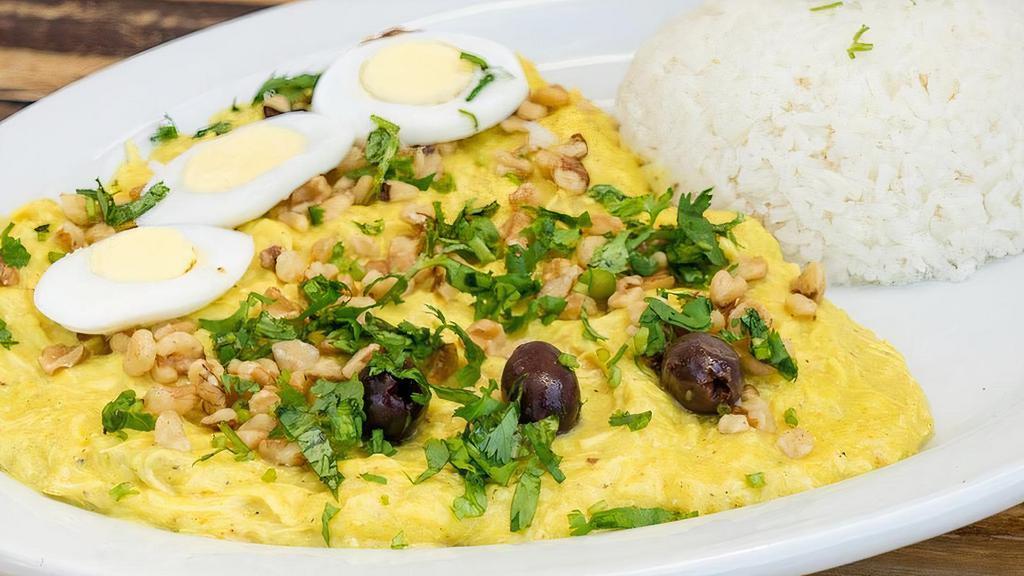 Aji de Gallina · A creamy stew made with shredded chicken breast cooked with Aji Amarillo chili, Parmesan cheese, cream, garnished with walnuts, olives, eggs, and cilantro, served with potato slices and garlic Jasmine rice.