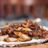 75. Sizzling Beef · Stir-fried sliced beef with green pepper, onion in black pepper sauce served on sizzling pla...