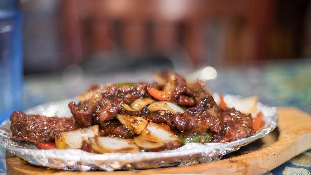 75. Sizzling Beef · Stir-fried sliced beef with green pepper, onion in black pepper sauce served on sizzling plate. Spicy.