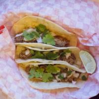 Adobo Tacos · Three tacos with shredded pork adobo, cilantro, onions, on corn tortillas.