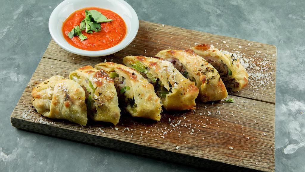 Patxi's Sausage Roll · Garlic-fennel sausage, bell-peppers, red onion and mozzarella rolled in rosemary parmesan dough with Calabrian chili sauce for dipping.