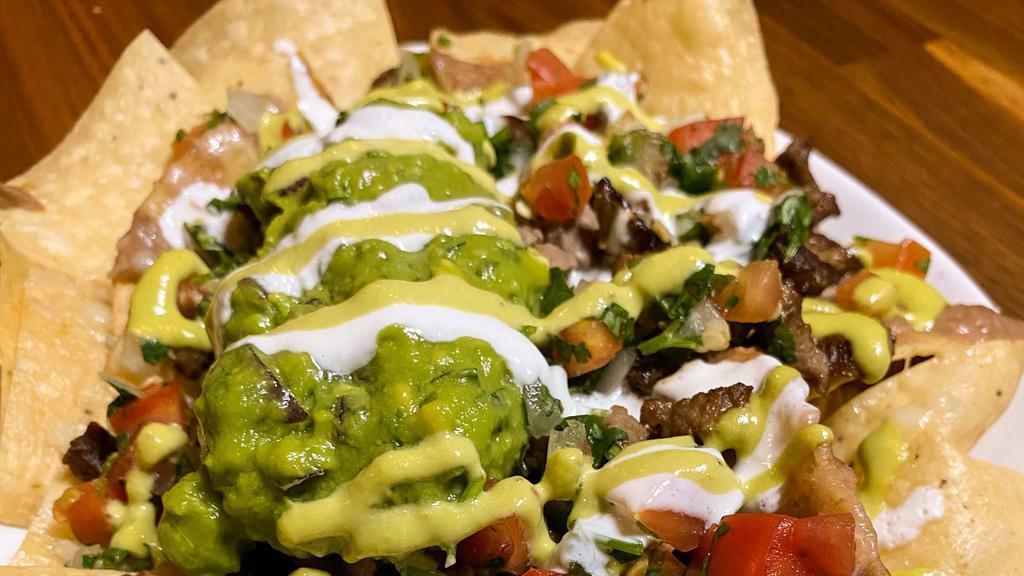 Nachos · Crispy chips, topped with Bronco Beans, melted cheese, jalapeño sauce, pico de gallo, crema, and fresh guacamole, with choice of meat.
