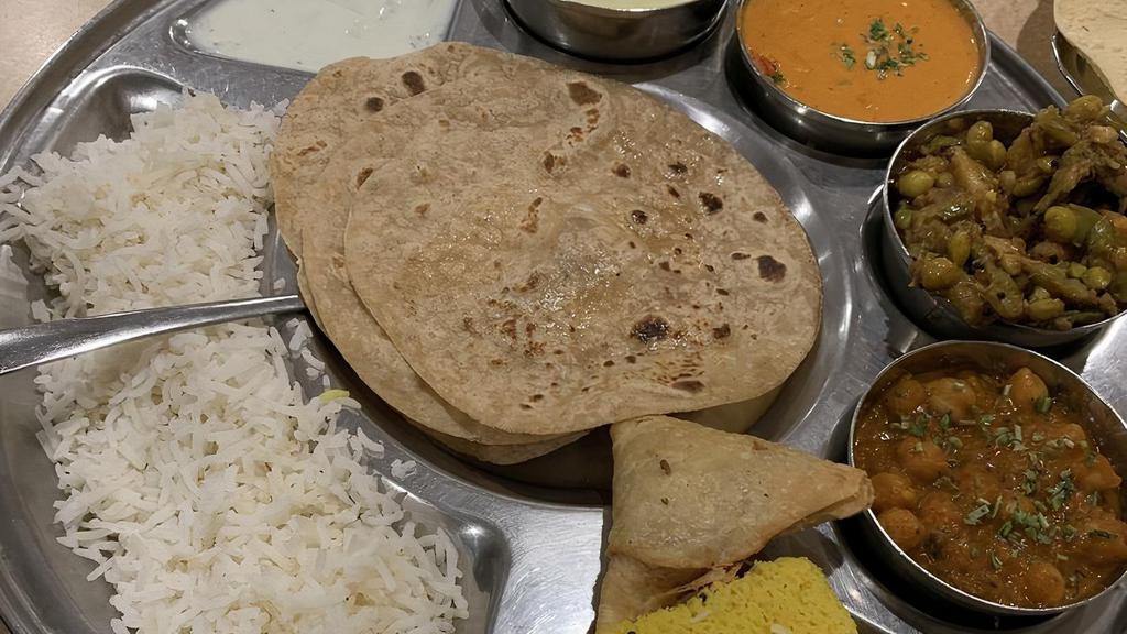 Punjabi Thali · Punjabi sabzi of the day, chole, undhiyu, rice, khadhi,  roti or puri, 2 appetizers, dessert, papad, raita and jeera chaas.