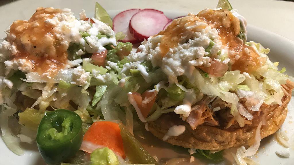 Sopes · Two home-made corn patties topped with beans, choice of meat, lettuce, sour cream, cheese and salsa. Served with rice and beans, sour cream, and guacamole.