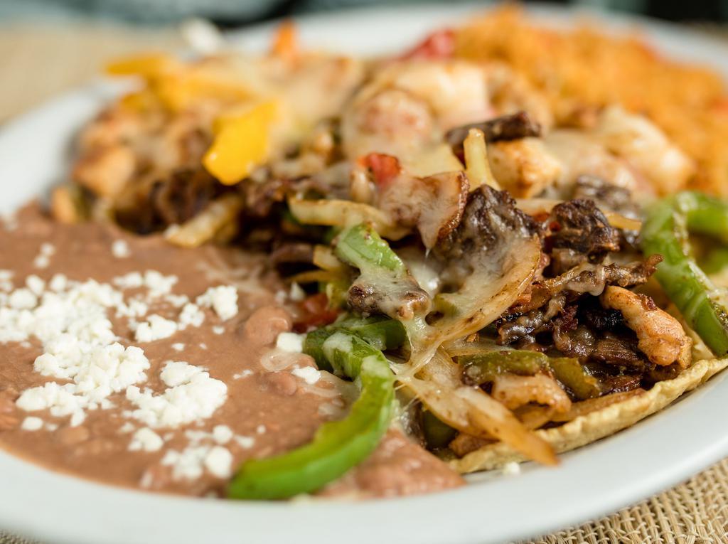 Alambre Grullense · Steak, shrimp, and chicken sauteed with bacon, onion, and bell pepper. Served over handmade tortillas and topped with melted cheese. Includes a side of rice and beans.