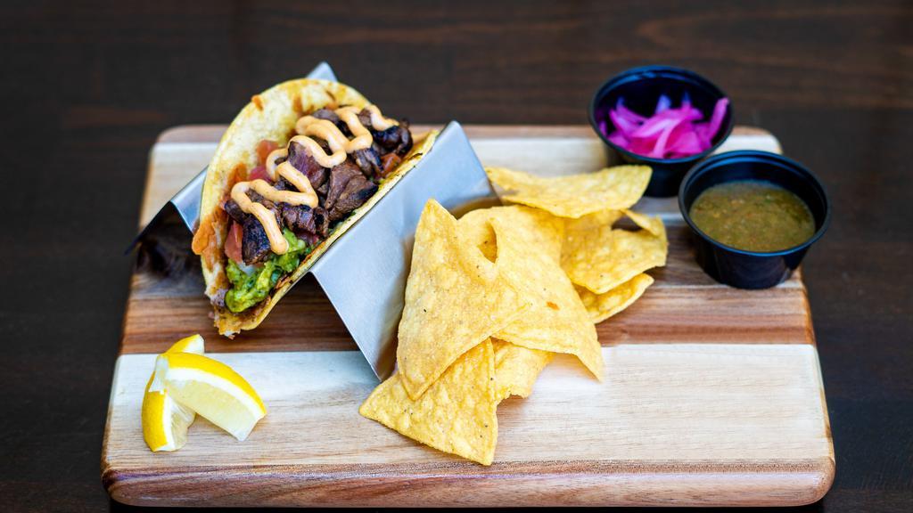 Steak Street Taco · Marinated skirt steak, grilled jack cheese, house-made guacamole, fresh pico de gallo, chipotle garlic aioli, cotija cheese, served on a warm tortilla and a side of pickled red onions and salsa.