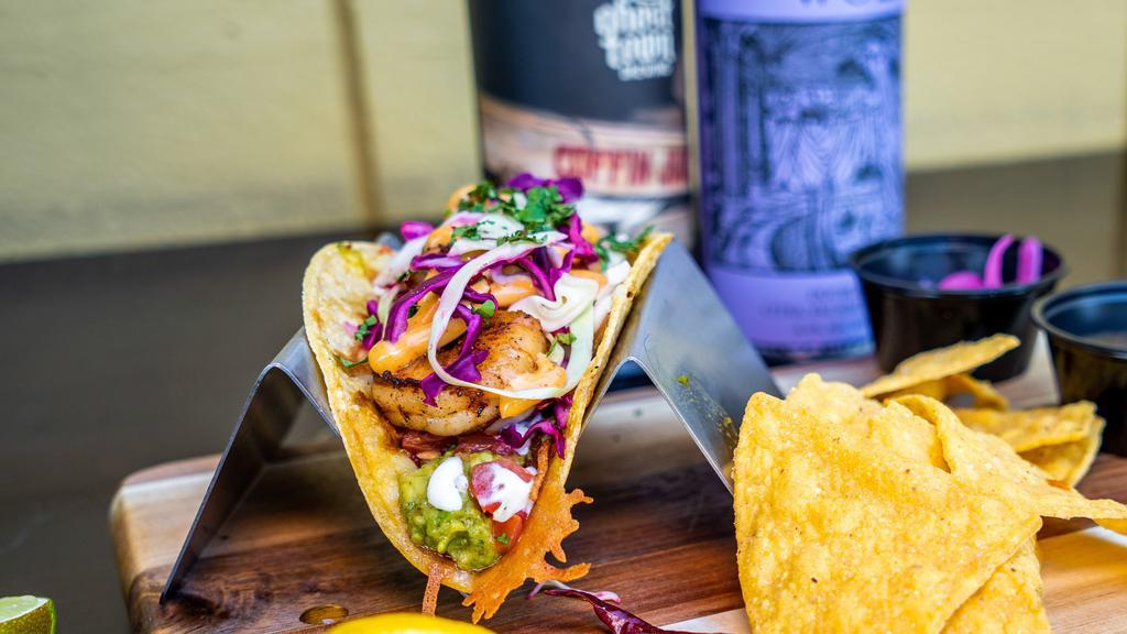 Shrimp Street Taco · Sautéed shrimp, grilled jack cheese, house-made guacamole, pesto cilantro sauce, fresh pico de gallo, chipotle garlic aioli, sour cream, mixed cabbage, served on a warm golden blend tortilla and a side of pickled red onions and salsa.