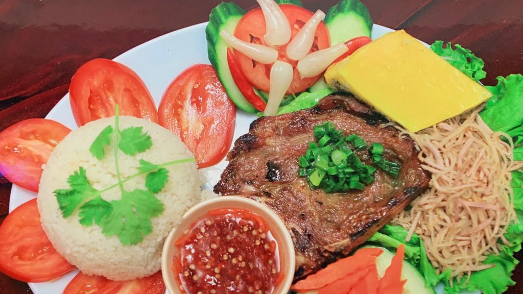 Grilled Pork Chop Plate (Com Tam Bi Cha Suong Nuong) · Served with broken rice (com tam), shredded pork, Vietnamese egg meatloaf (cha), salad, and fish sauce.