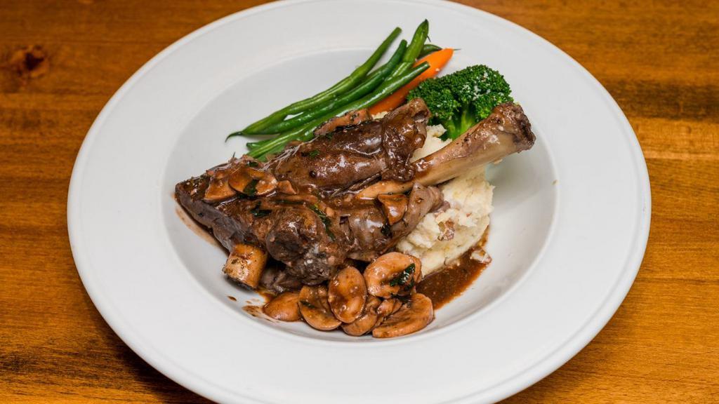Lamb Ossobucco · Lamb shank braised in red wine and herbs served with mashed potatoes and vegetables.