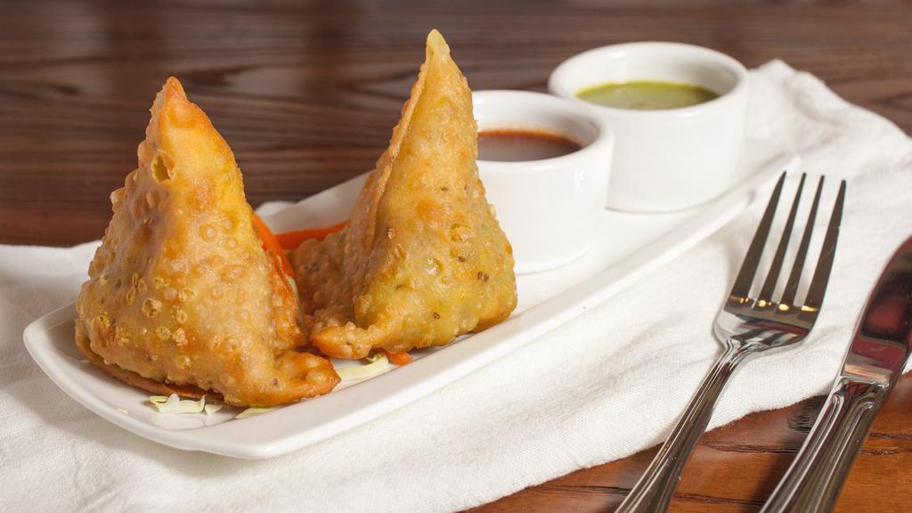 Vegetable Samosa · Hand wrapped, deep fried triangular pastry filled with spiced potato, peas and served with mint and tamarind chutneys.