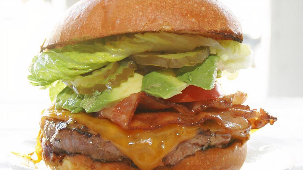 The New York Burger · A mouth-watering six-ounce burger served with bacon, cheddar cheese, avocado, chipotle remoulade, tangy caramelized red onions, tomato, pickles, romaine lettuce, bacon.