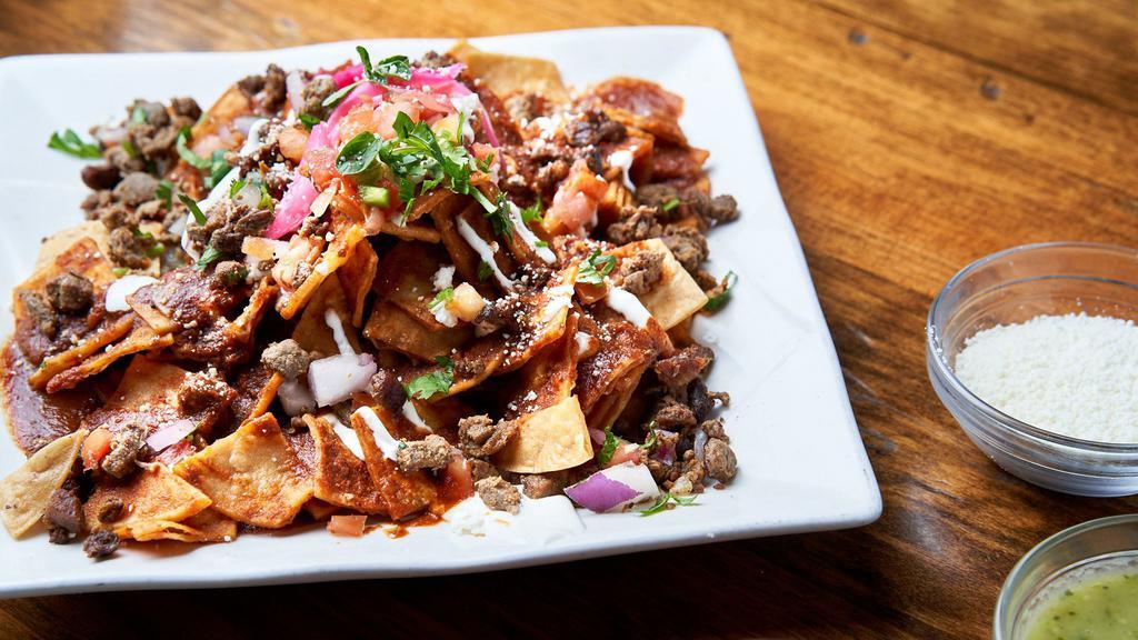 Chilakos · Tortilla chips, choice of meat, salsa roja, fresh oregano, red onions, queso fresco and Cotija and sour cream.