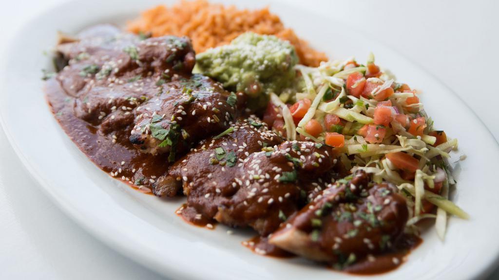 Pollo con Mole · Grilled chicken, homemade mole sauce topped with chayote, served with red rice & cabbage slaw.