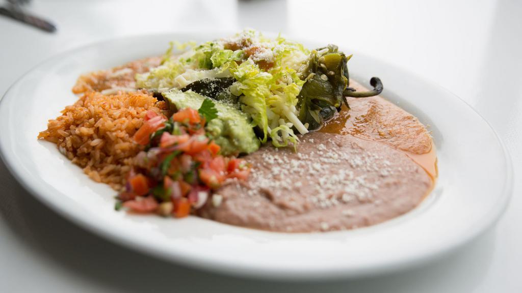 Chile Relleno · Fresh pasilla pepper stuffed with cheese, beans, served in a light tomato sauce with red rice.